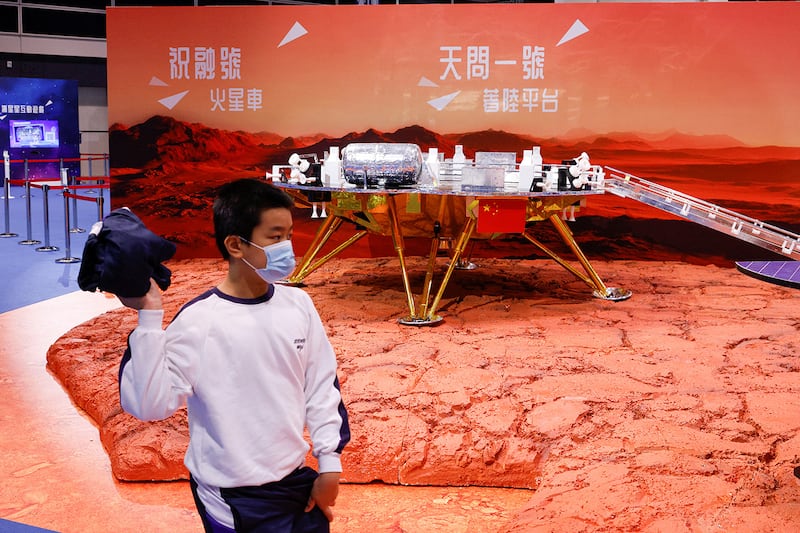 A student walks past a model of China’s Tianwen-1, a Mars rover mission, at the InnoTech Expo in Hong Kong, Dec. 13, 2022.