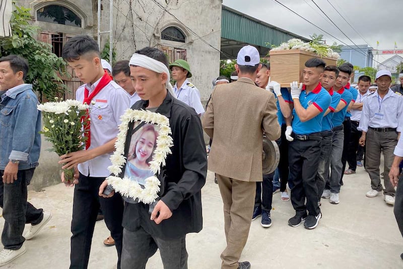 Bui Van Diep holds a portrait of his sister, Bui Thi Nhung, as her casket is carried to Phu Thang church ahead of her burial on Dec. 1, 2019 in the village of Do Thanh. (Associated Press)