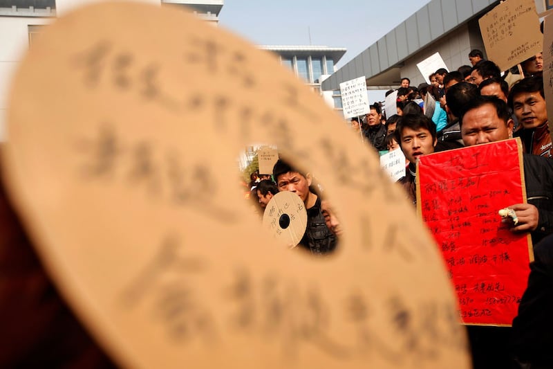 农民工在浙江义乌的招聘市场举起求职广告(路透社)