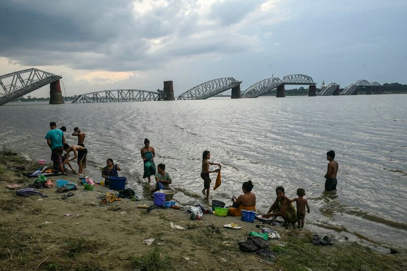 People take bath in the Irrawaddy River in front of the collapsed Ava Bridge, also known as the Inwa Bridge, in Mandalay on April 13, 2025, days after an earthquake struck central Myanmar.