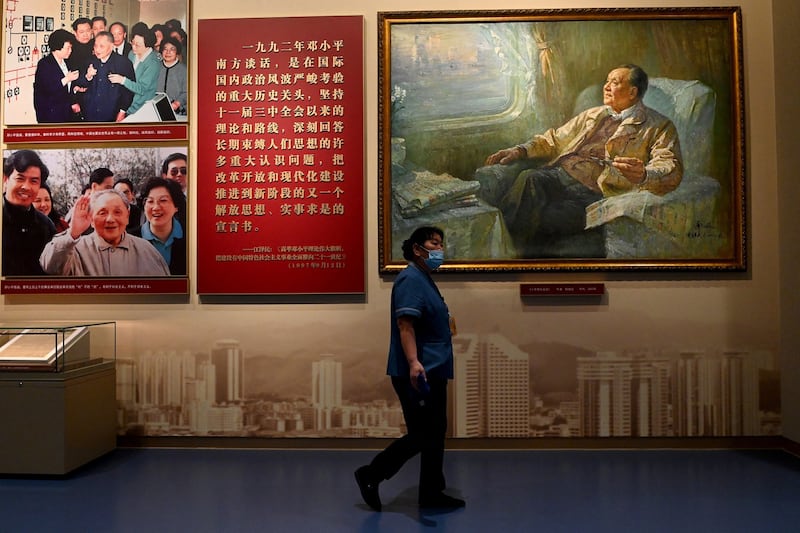A worker walks in front of a painting of late Chinese leader Deng Xiaoping at the Museum of the Communist Party of China in Beijing, June 25, 2021. Credit: Noel Celis/AFP