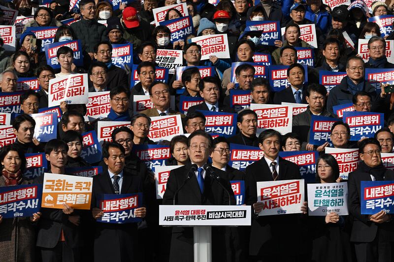 2024年12月4日,南韓國會議員及反對黨民主黨成員舉著寫著「尹錫悅應該辭職!」的標語牌(法新社圖片)